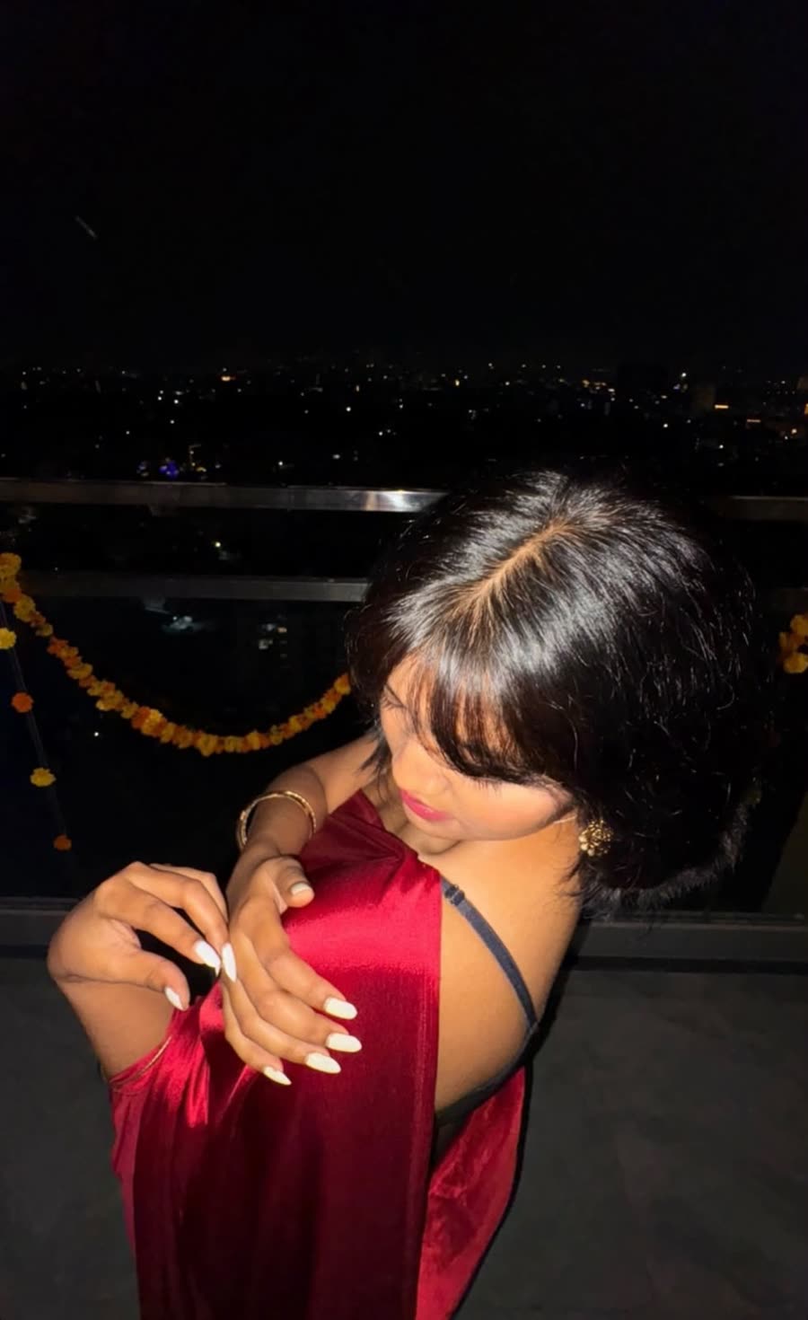 Anamika in a red saree on a rooftop at night